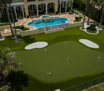 Aerial view of a backyard putting green with pool and palm trees
